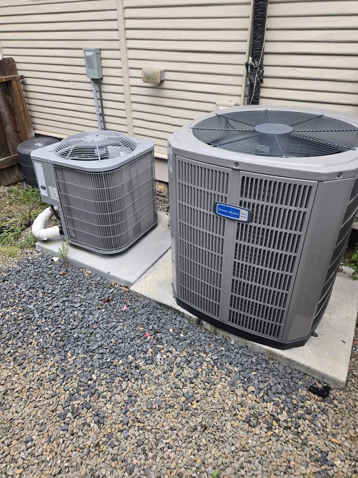 Two outdoor air-conditioning condensers on a concrete pad beside a Houston home