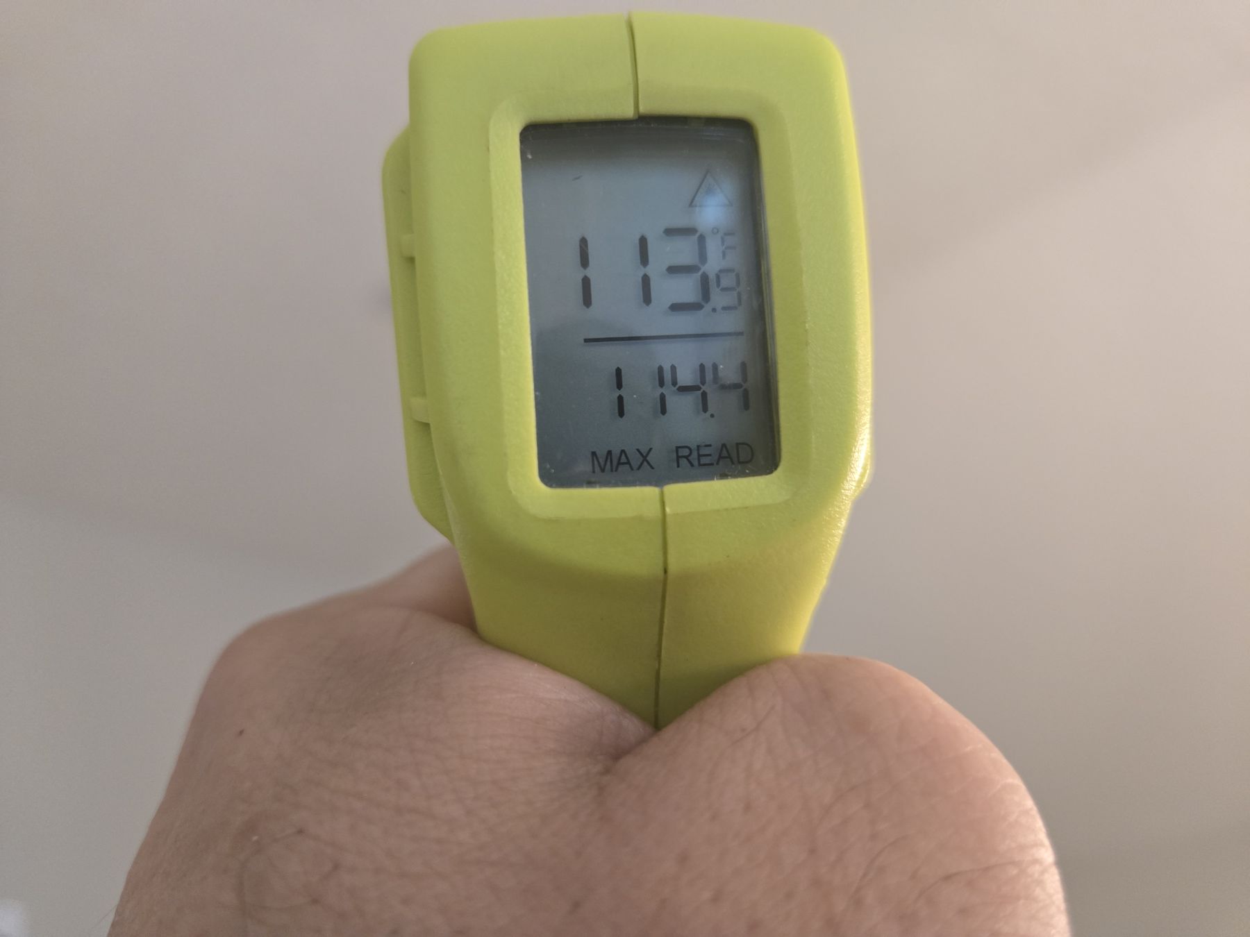 Handheld infrared thermometer showing a 114 degree F reading during a Cypress, Texas home inspection