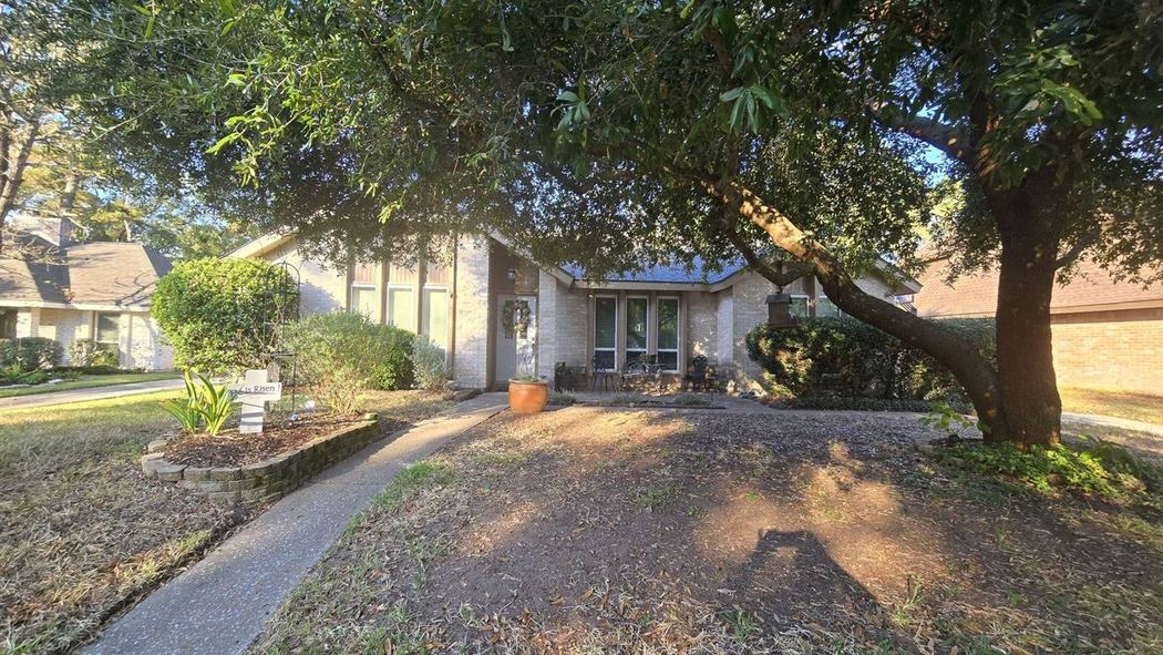 Single-story brick home exterior shaded by a large oak tree during a Kingwood home inspection