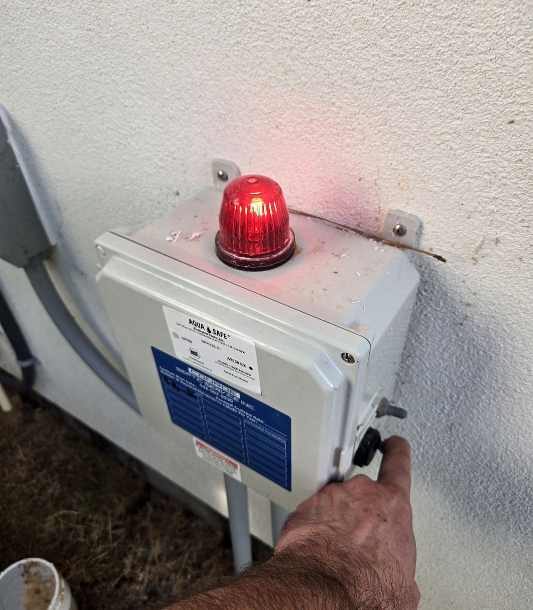 Septic alarm control box with a red beacon light mounted on an exterior wall