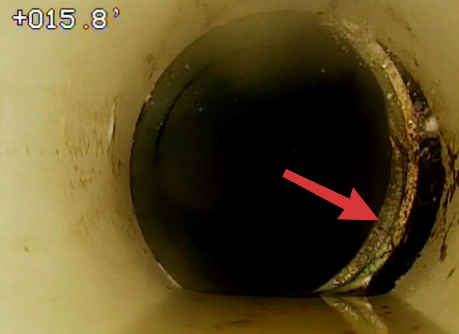 Sewer camera view of a pipe joint marked with an arrow, with an on-screen distance of about 15.8 feet
