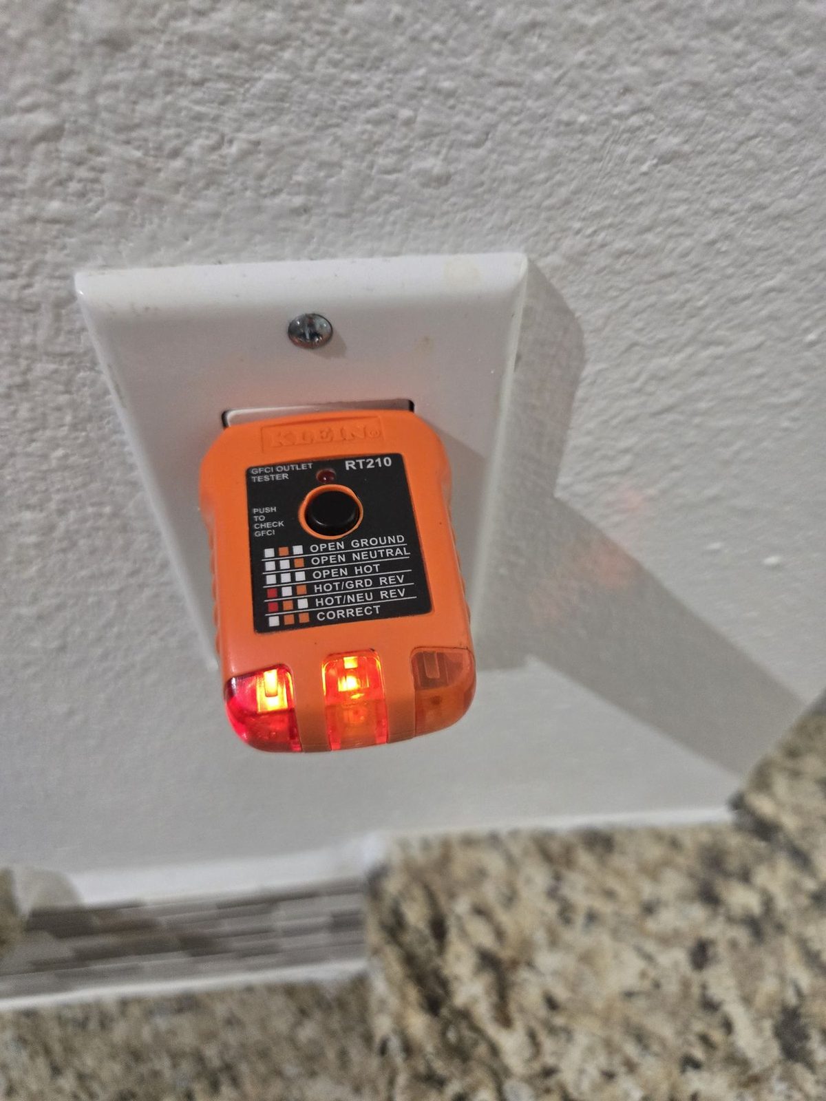 Orange receptacle tester plugged into an outlet during an electrical check in The Woodlands, Texas
